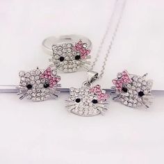 three hello kitty necklaces with pink and white crystals on them, sitting next to each other