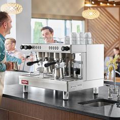 a man standing in front of a counter with a coffee machine on top of it