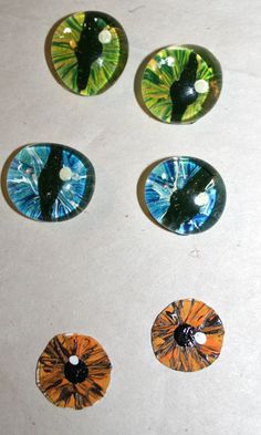 four different colored glass buttons sitting on top of a white table next to each other