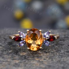 an orange and blue ring sitting on top of a gray rock with three different colored stones