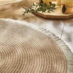 a round rug is on the floor next to candles and a tray with greenery