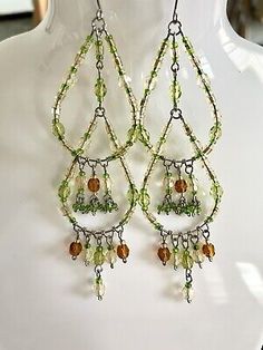 a pair of green and brown earrings on a white mannequin