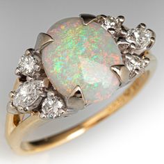 an opal and diamond ring, with three diamonds on the bottom one in yellow gold