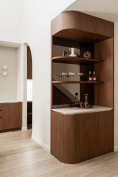 an empty kitchen with wooden shelves and white counter tops on the wall, along with hardwood flooring