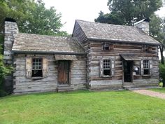 an old log cabin sits in the grass