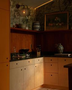 a kitchen with wooden cabinets and black counter tops in the evening light from an open window