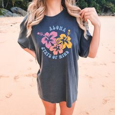 Embrace the tropical vibes and VSCO-inspired style with the Comfort Colors "Aloha Hibiscus" Shirt. This trendy tee is a summer essential, perfect for beach days and sunny adventures. With its hibiscus flower design and beachy aesthetic, it adds a touch of tropical fashion to your wardrobe. Let the vibrant colors and beach vibes transport you to paradise. All clothing and accessories from The Southern Thistle are handmade-to-order, just for you! ☺️ Experience the epitome of comfort with Comfort C Casual Multicolor Tops For Surfing, Tropical Multicolor T-shirt For Vacation, Multicolor Hawaiian T-shirt For Beach Season, Tropical Printed Tops For Surfing, Tropical Printed Tops For Resortwear, Summer Hawaiian Shirt With Graphic Print For Surfing, Tropical Palm Tree Print T-shirt For Spring, Spring Tropical T-shirt With Palm Tree Print, Spring Vacation T-shirt With Hibiscus Print