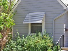 a gray house with white trim and a small window