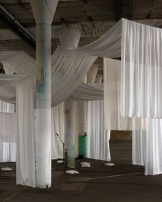 an empty room with white drapes hanging from the ceiling