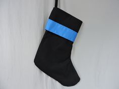 a black christmas stocking with a blue ribbon hanging on a white wall in the corner