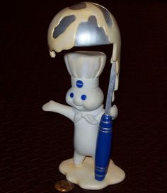 a plastic toy with a chef holding a knife and an umbrella on it's head