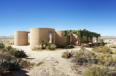 the desert house is surrounded by trees and bushes, with two round structures on each side