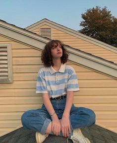 a young woman sitting on top of a roof next to a house with her eyes closed