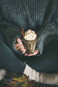 a person holding a cupcake in their hands with cinnamon sticks sticking out of it