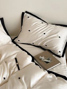 a bed with white sheets and black polka dots on the covers, along with a book