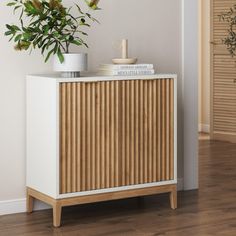 a plant is sitting on top of a cabinet in a room with hardwood floors and white walls