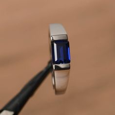 It is a lab sapphire ring. The main stone is 5mm*7mm emerald cut, weight about 1.16 carats.The basic metal is sterling silver and plated with rhodium.To change the metal to a solid gold (white/rose) or platinum is also available, please ask for a quotation if you want.You can also go to my shop Home for more elegant rings: https://www.etsy.com/shop/godjewelry?ref=hdr_shop_menu More sapphire rings: https://www.etsy.com/shop/godjewelry?ref=seller-platform-mcnav&section_id=20715031Customization Silver Ring With Diamond For Men, Sapphire Ring Men, Sapphire Proposal Ring, Sapphire Ring Silver, East West Ring, Kids Ring, Tanzanite Rings, Stones Rings, Elegant Rings