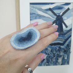 a woman's hand holding a ring with an image of a windmill in the background