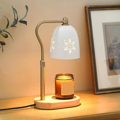 a table lamp sitting on top of a wooden desk next to a framed photograph and a jar