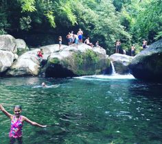 a woman standing in the middle of a river with rocks and people on top of them