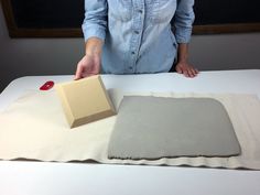 a woman standing over a white table with a box on it