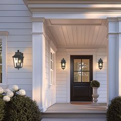 the front door of a white house with two large lanterns on it's side