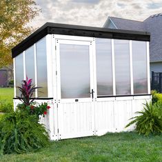 a white and black shed sitting in the grass