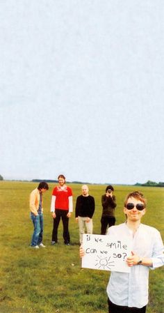 a group of people standing on top of a grass covered field with a sign in front of them