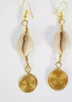 two pairs of earrings with gold spirals and white shells on them, hanging from hooks