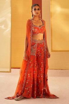 Orangish red silk organza cape with floral print and zardosi and pitta embroidery. Comes with sharara and a blouse.
Components: 3
Pattern: Printed, Embroidered
Type Of Work: Floral, Zardosi, Pitta
Neckline: Sweetheart
Sleeve Type: Cape : Flared Sleeves, Blouse : Sleeveless
Fabric: Silk organza
Color: Orange,Red
Other Details: 
Pocket detailing on sharara
Note : Outfit worn by the model on the left is not for sale.
Occasion: Mehendi and Haldi - Aza Fashions Bollywood Style Saree Palazzo Set With Floral Embroidery, Traditional Front Open Sharara With Dupatta, Traditional Front Open Sharara With Resham Embroidery, Floral Embroidered Traditional Drape Sets For Navratri, Traditional Drape Sets With Floral Embroidery For Navratri, Navratri Sets With Floral Embroidery And Traditional Drape, Traditional Front Open Choli With Dupatta, Navratri Front Open Sharara With Resham Embroidery, Embroidered Orange Palazzo Set