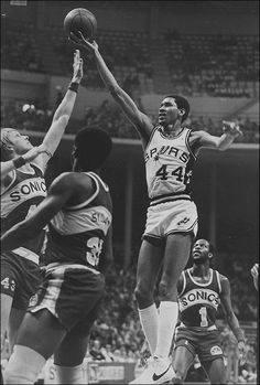 an old black and white photo of a basketball player jumping up to dunk the ball