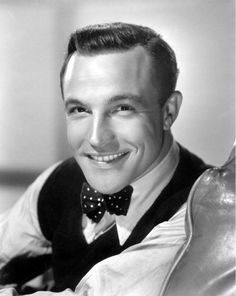 a black and white photo of a man wearing a bow tie smiling at the camera