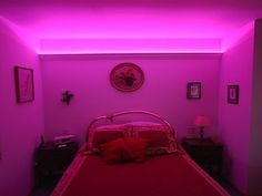 a bed in a room with pink lights on the walls and red blankets on the bedspread