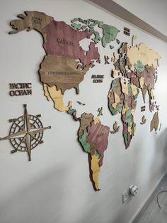 a map of the world is mounted on a wall with wooden cutouts and compasses