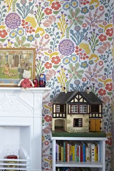 a doll house sitting on top of a book shelf next to a fireplace and wallpaper