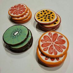 four decorated cookies sitting on top of a white table next to orange slices and black dots