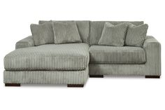 a gray couch with pillows on it and a footstool in the middle, sitting against a white background