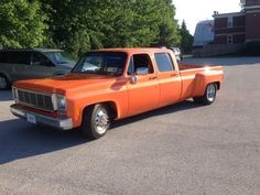 an orange pick up truck parked in a parking lot