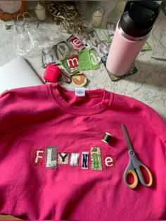 a pink shirt with the word flunke spelled out on it next to scissors and other items