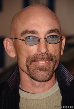 a bald man wearing glasses and a sweater