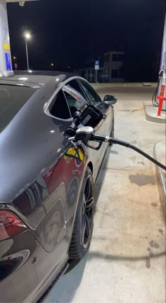 a car is being charged at a gas station by an electric charger plugged into it