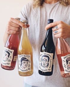 a woman holding three bottles of wine in each hand and another one with a man's face on it