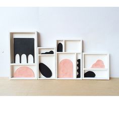 three abstract paintings in white frames with pink and black shapes