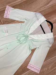 "Here we have fabulous vintage Shadowline dressing gown from the 1970s. Made up of 100% soft and stretchy nylon, this gown features a full button up front with fabric covered buttons. Adorable lace trimmed pocket on one side. Drawstring tie waist allows for a more tailored look. Snap closure underneath top button. Lovely light mint green color. There is a small very faint discoloration at the midriff area between the buttons, I was unable to get it out with washing it. Price has been adjusted to Fitted V-neck Daywear Robe, Fitted V-neck Robe For Daywear, Fitted Vintage Robe For Daywear, Vintage Long Fitted Robe, Fitted Long Sleeve Robe With Lace Trim, Fitted Robe With Lace Trim And Long Sleeves, Fitted Lace Trim Robe For Spring, Fitted Robe With Lace Trim For Daywear, Fitted Lace Trim Robe For Daywear