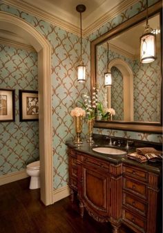 a bathroom with blue and gold wallpaper, wooden vanity and white flowers on the counter