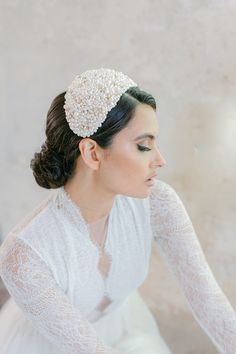 a woman in a white dress is wearing a headpiece with pearls on it's hair