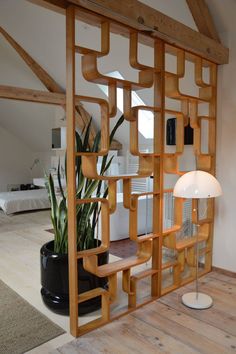 a room divider made out of wood with a plant in the middle and a lamp on top