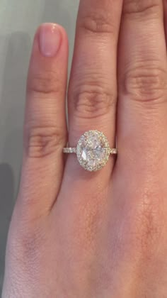 a woman's hand with a diamond ring on top of her finger and an engagement band