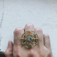 "What a knockout! This textured raw brass gold tone ring is set with the Earth in glass surrounded by 8 different phases of the moon in a round halo. Celebrate the cosmos and our planetary home with this piece of galaxy jewelry! Ring Size: Adjustable Design Size: 1 1/4\" (3.2cm) Materials: Raw brass, glass ★ These are individually handcrafted and the particular piece you receive may vary slightly from what is pictured. These are also not 100% waterproof, so please avoid submerging them in water. Celestial Metal Ring Jewelry, Celestial Style Metal Ring Jewelry, Handmade Gold Celestial Moonstone Ring, Gold Brass Crystal Ring For Gifting, Gold Brass Crystal Ring Gift, Celestial Style Gold Round Rings, Gold Celestial Moon Ring, Gold Celestial Ring With Moon Phase, Celestial Gold Moonstone Ring With Moon Phase