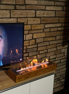 a man is on the television screen with flames in front of him and his face glowing